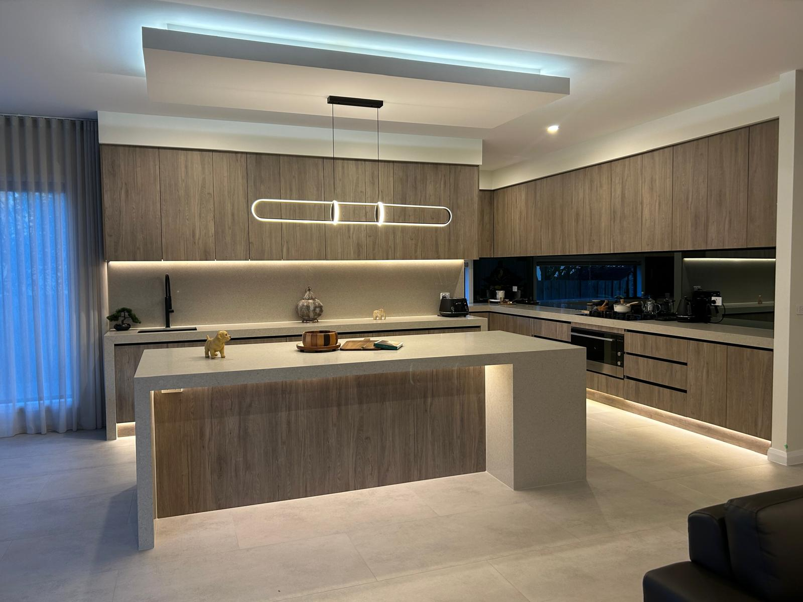 Modern kitchen interior with wooden cabinetry, large island, and sleek overhead lighting. Modern kitchen interior with wooden cabinetry, large island, and sleek overhead lighting.