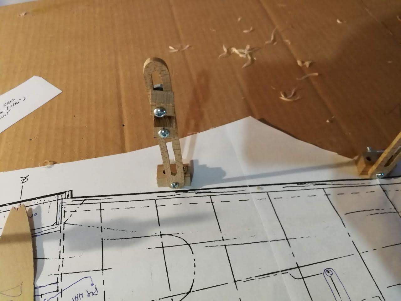 Modern office setup with a computer displaying 3D aircraft design and a model airplane next to a keyboard and blueprint.