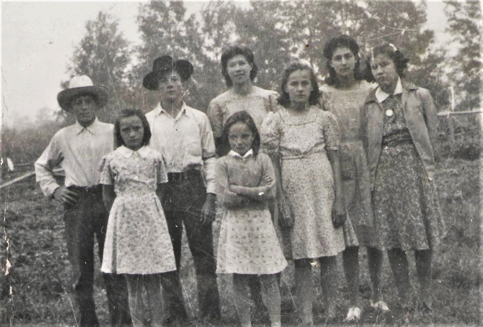 The girls in the front row (L-R) Are Olga Sanderson, Stella Sanderson, Velma Sanderson, and Alice Lizotte.
The back row is where we need help identifying - the Two boys on the left are labelled as "A Sanderson and Lizotte" though we aren't sure first names nor which is which. Could it be Harold Sanderson in the black hat? The girls in the back (L-R) are Ruby Lizotte and Margaret Lizotte. Based on the apparent ages of the known children we are guessing this photo is from the early 1940's

--EDIT--

The gentleman in the back row are (L-R) Eugene Lizotte and Clarence Sanderson.

2019.24.315 / Lizotte, Maria