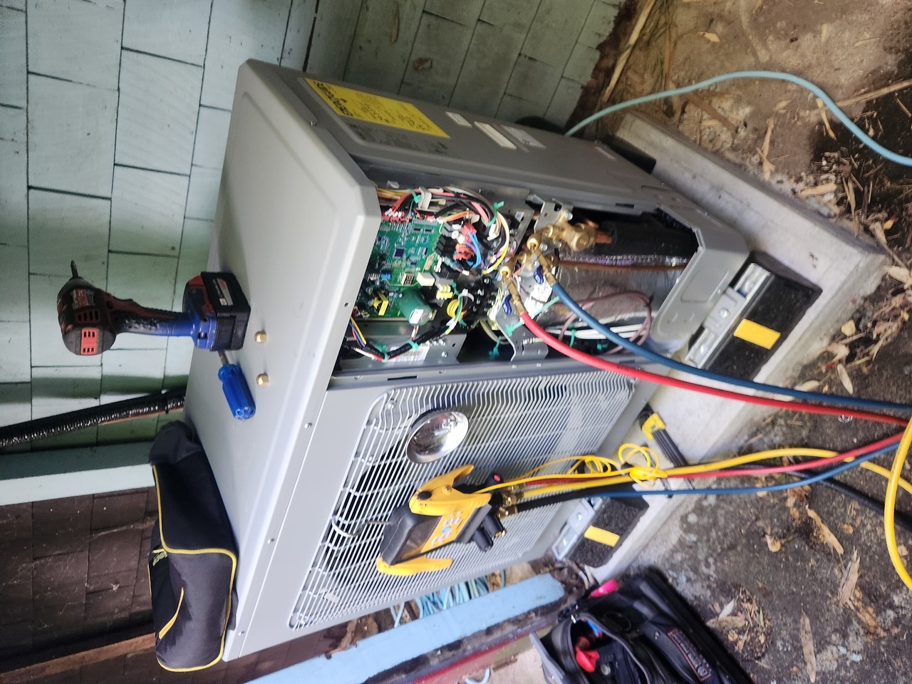 Modern two-story house with large windows, surrounded by lush greenery and trees on a sunny day.