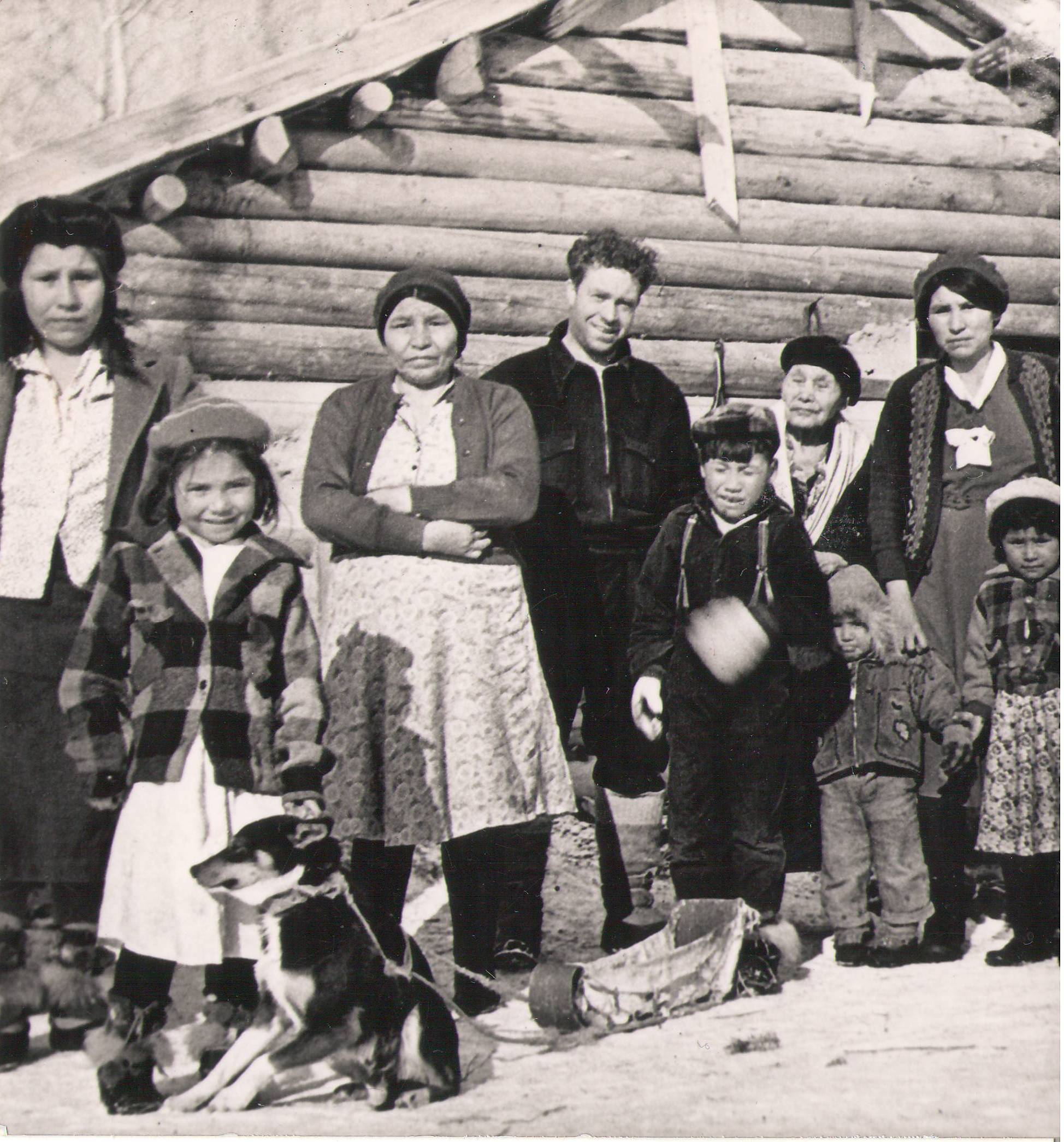 We are unsure where this picture was taken. We think the gentleman in the centre (Black Coat) is Harry Borbridge - he spent time all over northern Alberta. The other individuals are potentially a family that hosted him on his adventures. In any case we know very little about these people and would love to know more! Drop any details you wish to share in the comments!
990.4.79.167 / Reid, Gordon

PS. how cute is the girl and her sled dog in training in the front?

*EDIT*

The Group has been identified as such (L-R)  Maria Tallcree, Florence Nanooch, Nancy Metsikassus, Father Vandersteen, and Fred Tallcree. The other people are still unknown.