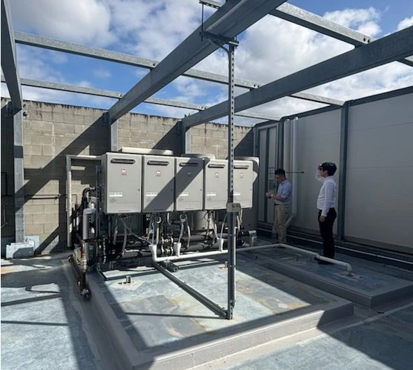 Engineers inspecting industrial water treatment system with stainless steel tanks, insulated pipes, valves and gauges