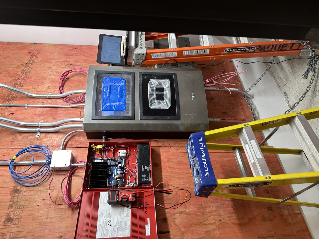 Trois personnes discutant autour d'une table avec des documents, dans un bureau, portant des badges d'identification.