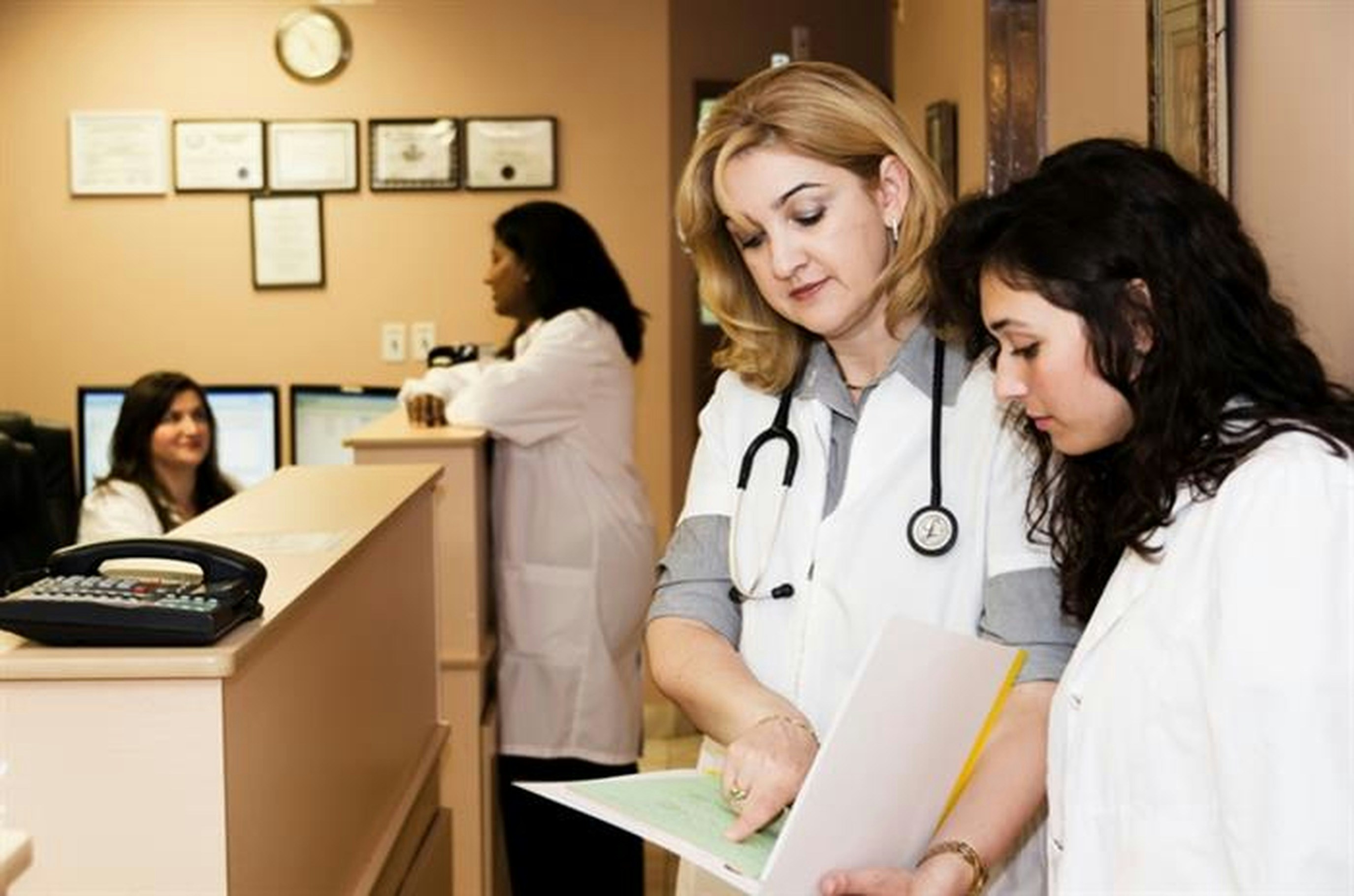 Healthcare professionals discussing patient records on tablets in modern hospital office Healthcare professionals discussing patient records on tablets in modern hospital office