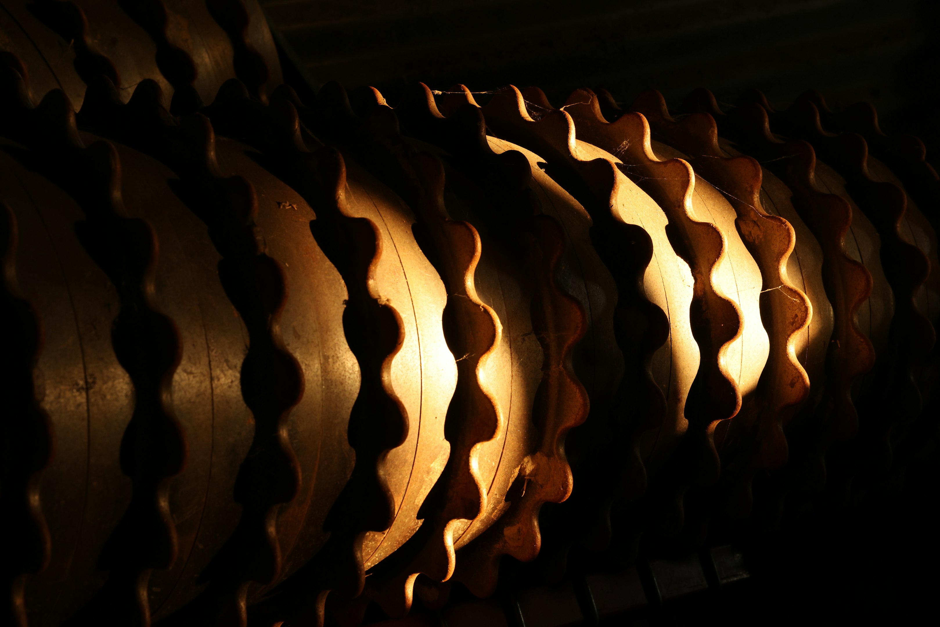 Close-up of industrial machine gears with textured, wavy patterns in warm lighting.