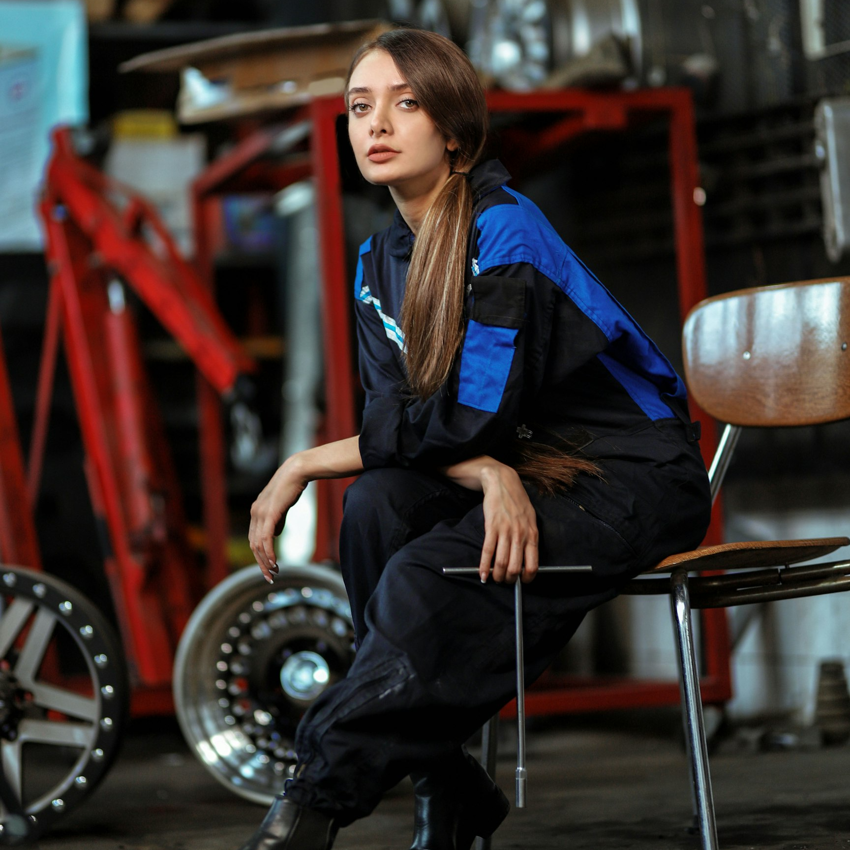 Smiling man in a blue work jacket standing in a modern industrial facility with tractors in the background.