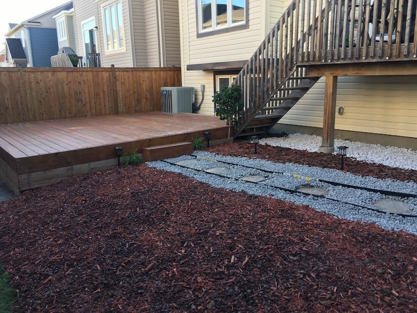 Modern outdoor patio with wooden decking, comfortable seating, dining area, and scenic view of trees and sky.
