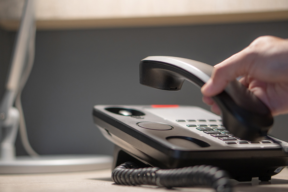 A hand holding an office telephone