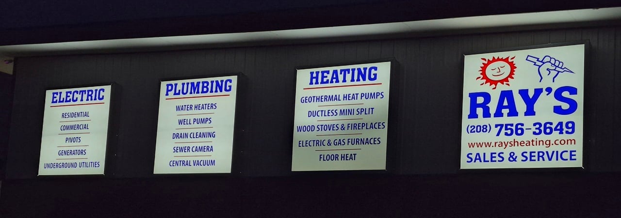 Signs on a building advertising electric, plumbing, and heating services by Ray's with contact information and service details.