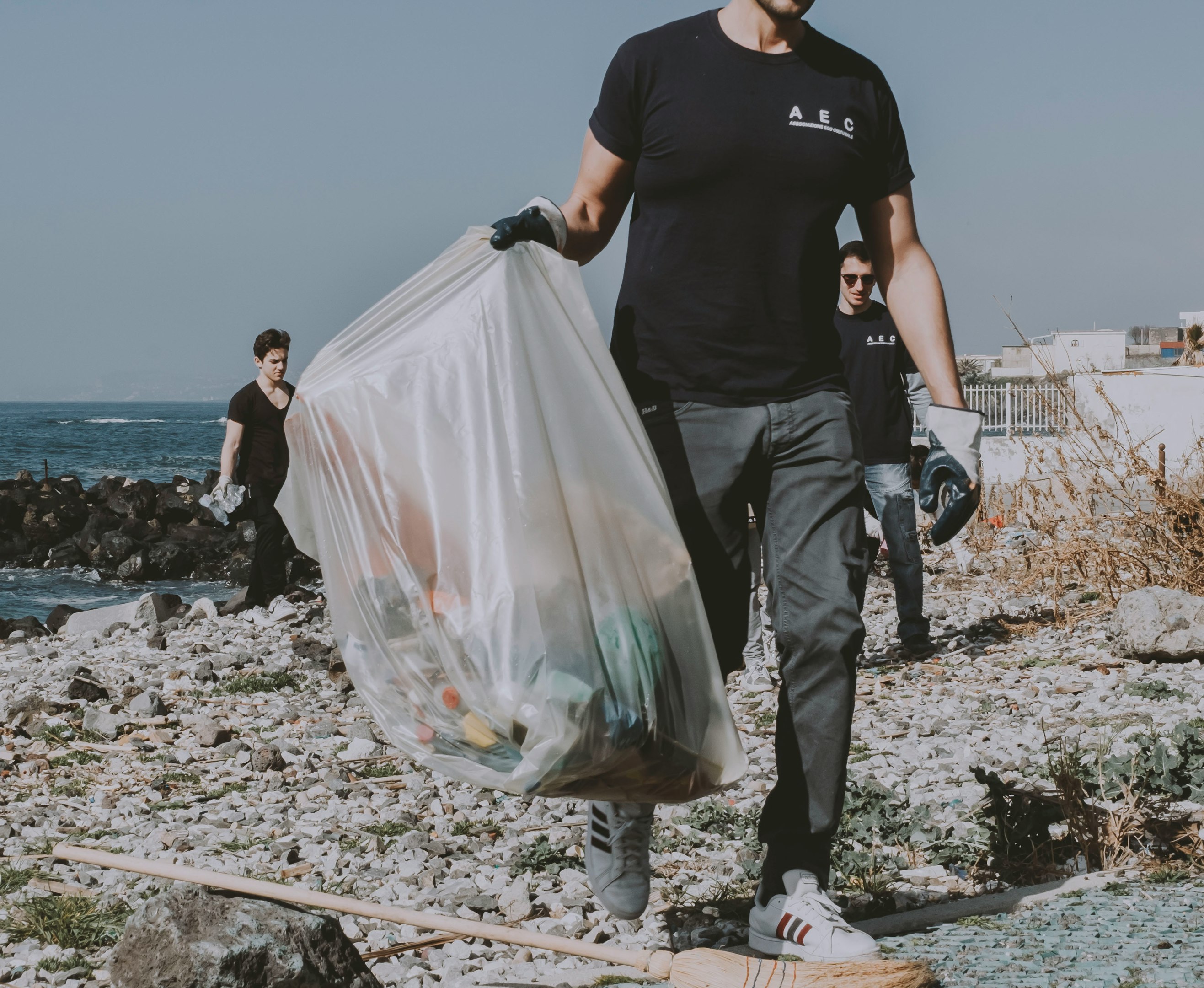 ein Mann, der am Strand spaziert und einen Sack Müll trägt