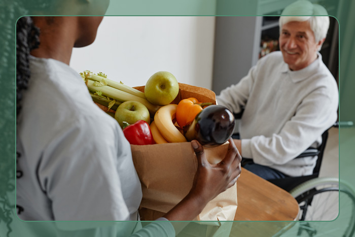 A young male carrying a bag of groceries for an elderly man