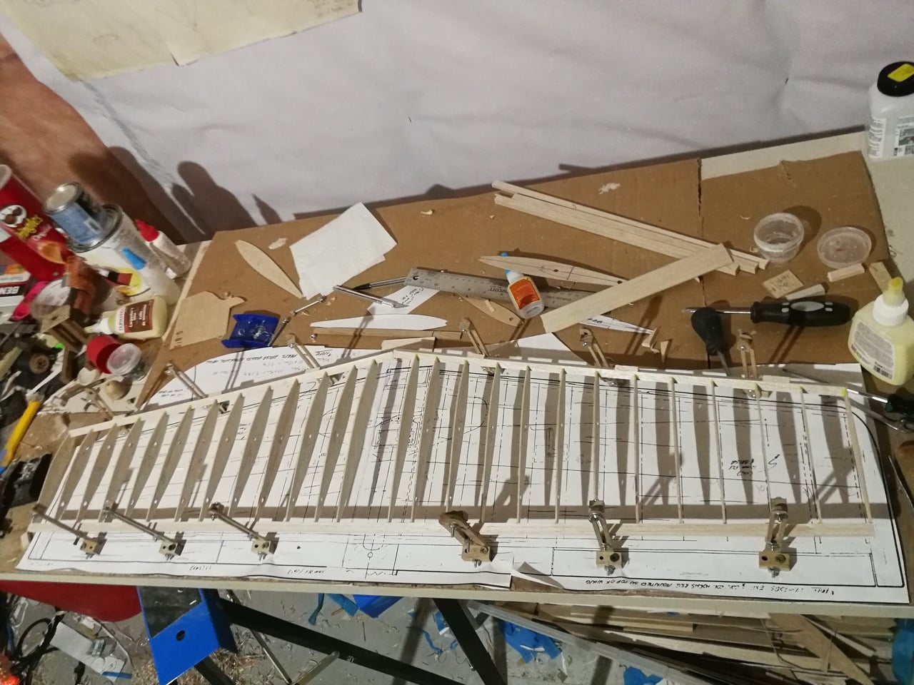 Vintage orange and white biplane in a spacious hangar with industrial lighting.