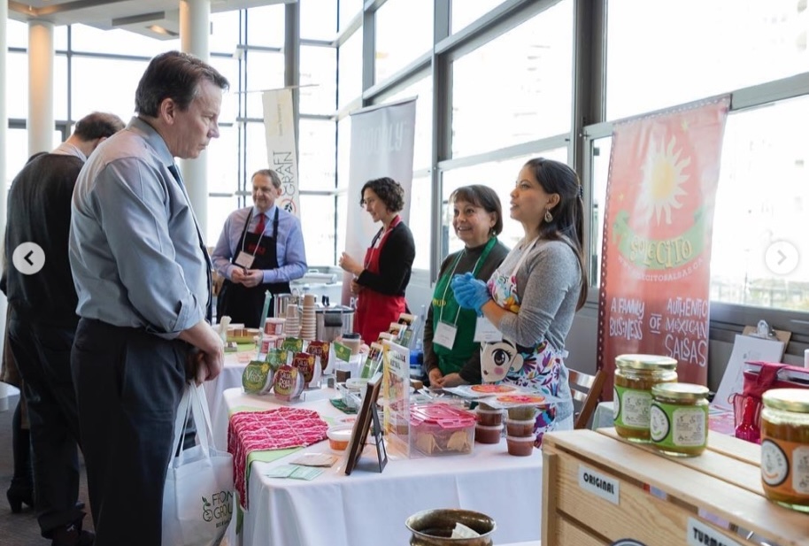 Delicious flatbread topped with fresh vegetables, crumbled cheese, and herbs, served on a wooden plate with other colorful dishes in the background.