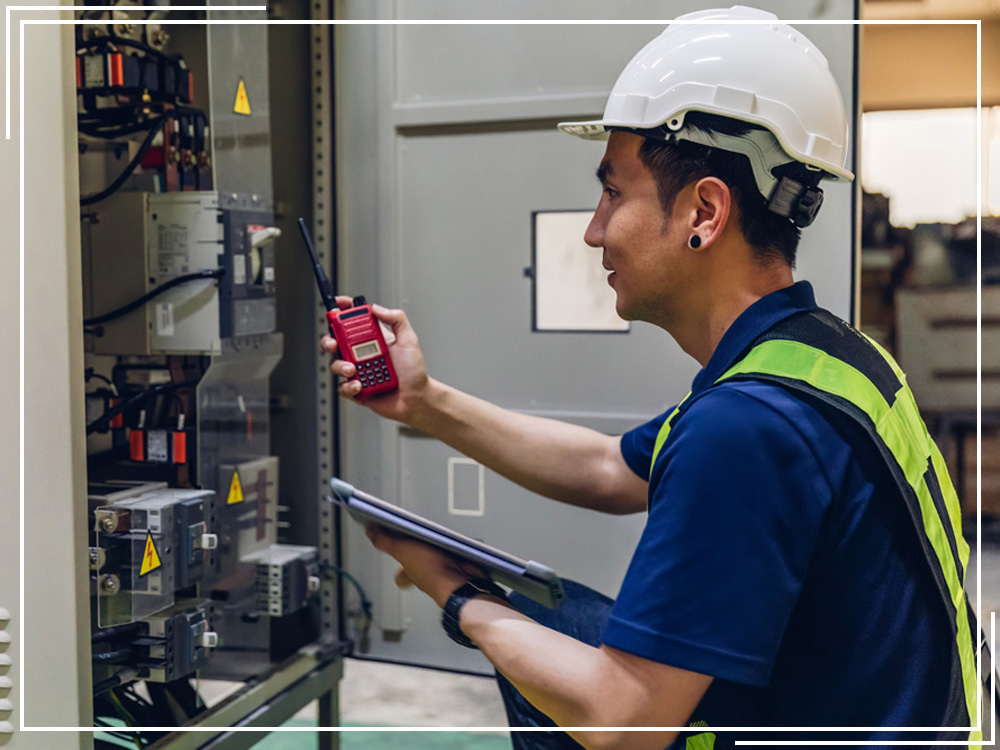 A man in a hard hat troubleshooting electrical box