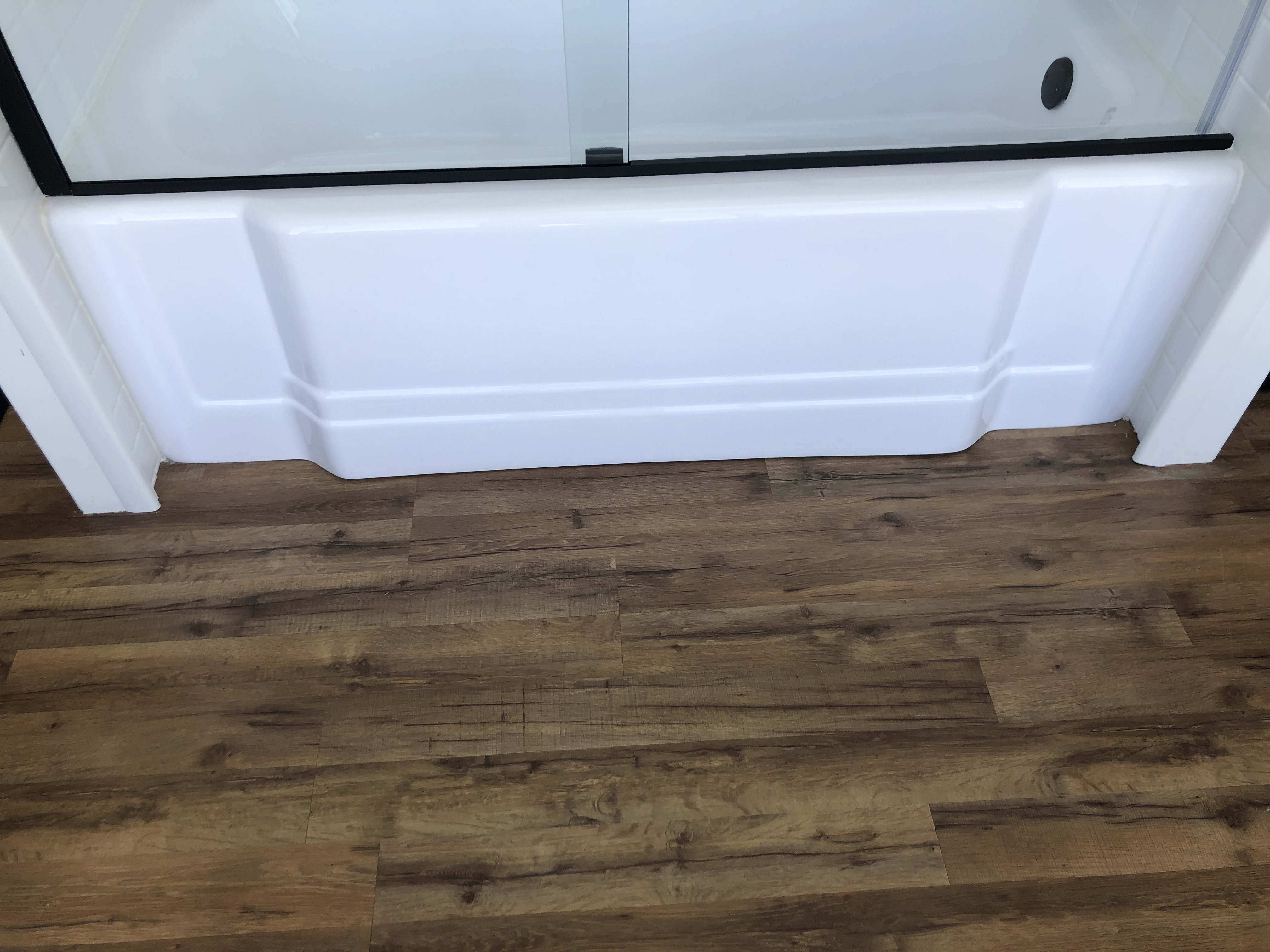 Modern minimalist bathroom with white fixtures, glass shower, large bathtub, and indoor plants.