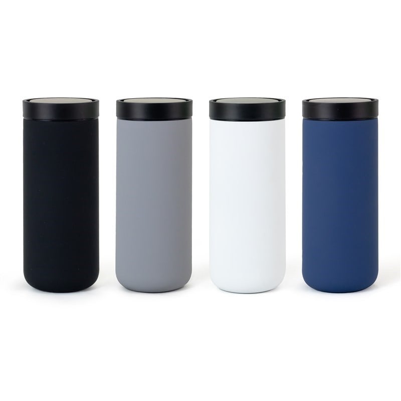 Person holding a white handheld device next to folded jeans and two beverage cans on a rustic wooden table.