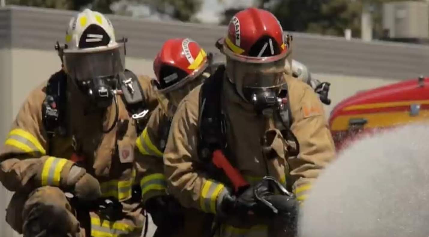 Three Firefighters in turnout gear crouching  in the ready