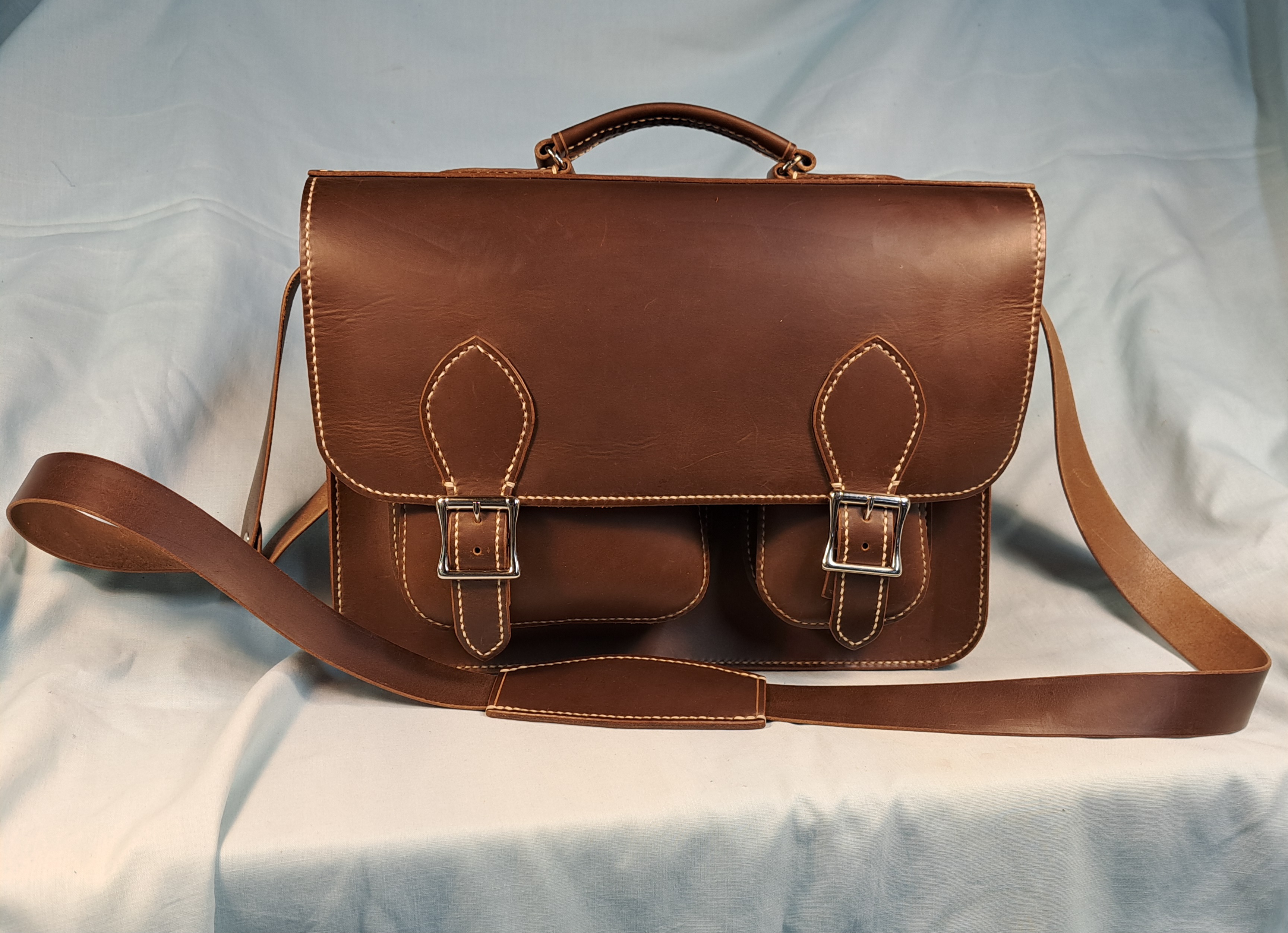 A brown customer leather bag with buckles and stitching
