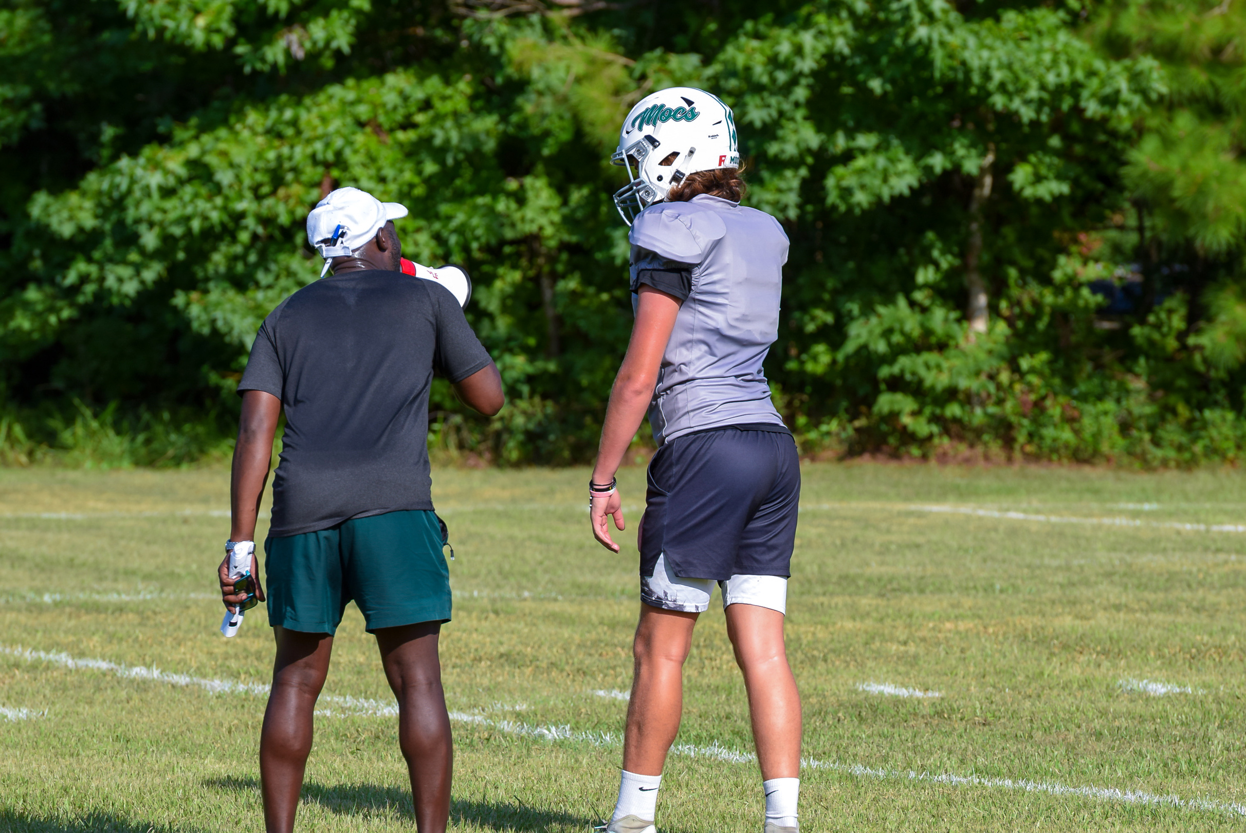 Football coach and player discussing strategy on practice field