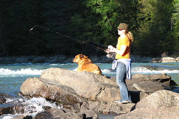 A Woman Fishing With Her Dog