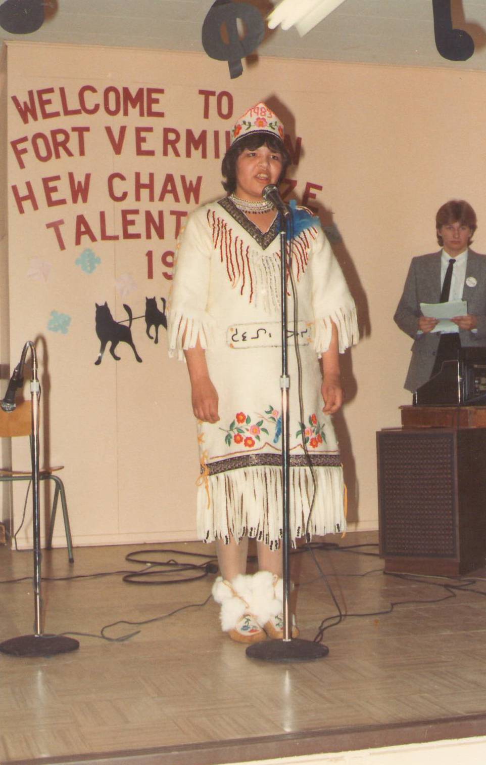 This photo comes from the 1983 Hew Chaw Daze Talent show. This lady is beautifully dressed and were sure sounds just as good - we just aren't sure who she is!
Bonus Question- We also don't know who the gentleman in the background is. He seems to be the presenter in other photos - but thats the best we have!

*EDIT*
This performer has been identified as Lorraine Auger and the gentleman in the back as Mark West.
998.1.60.169 / Newman, Jack and Pearl