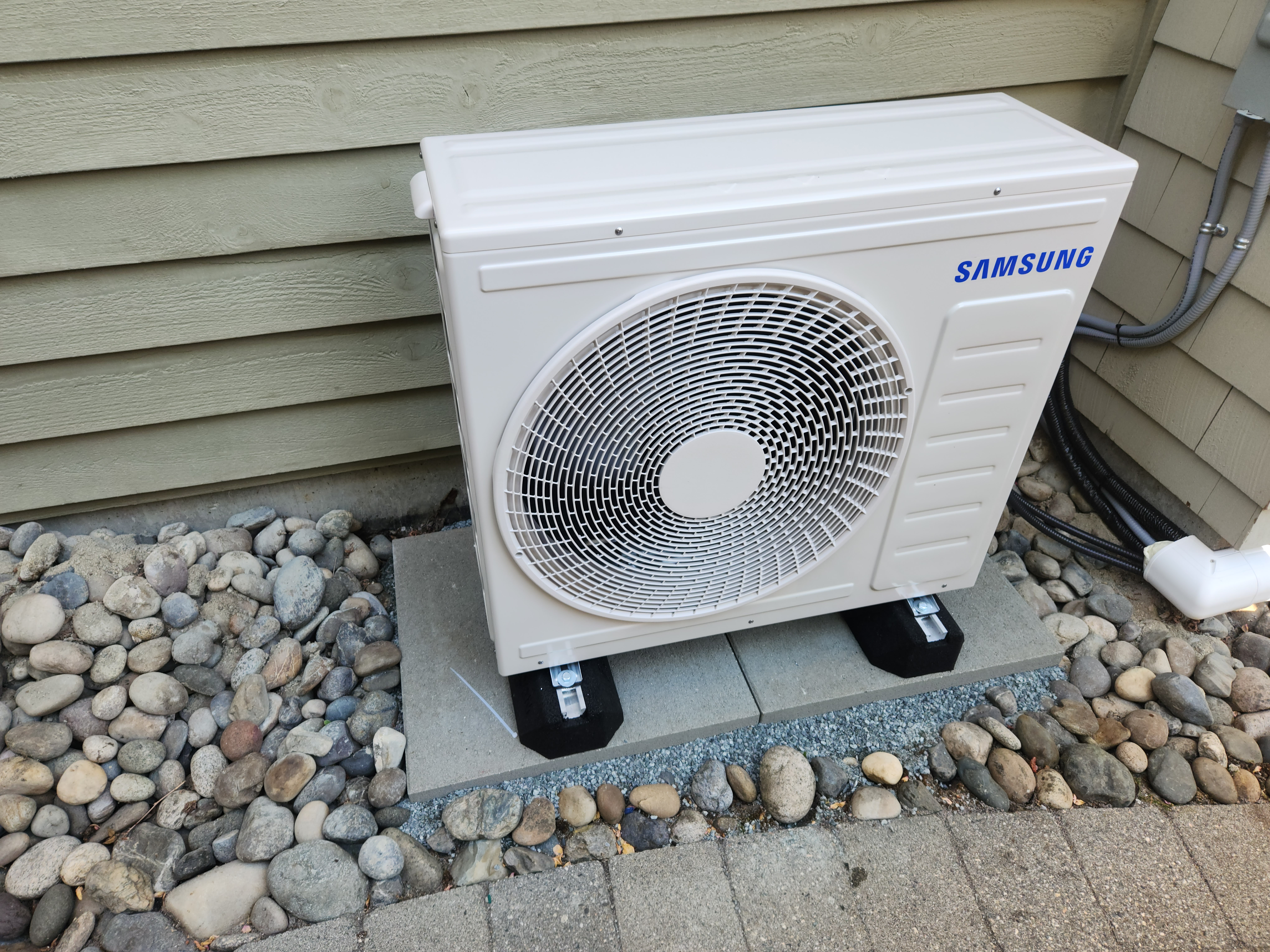 Modern industrial room with two large air conditioning units, exposed brick wall, and potted plants.