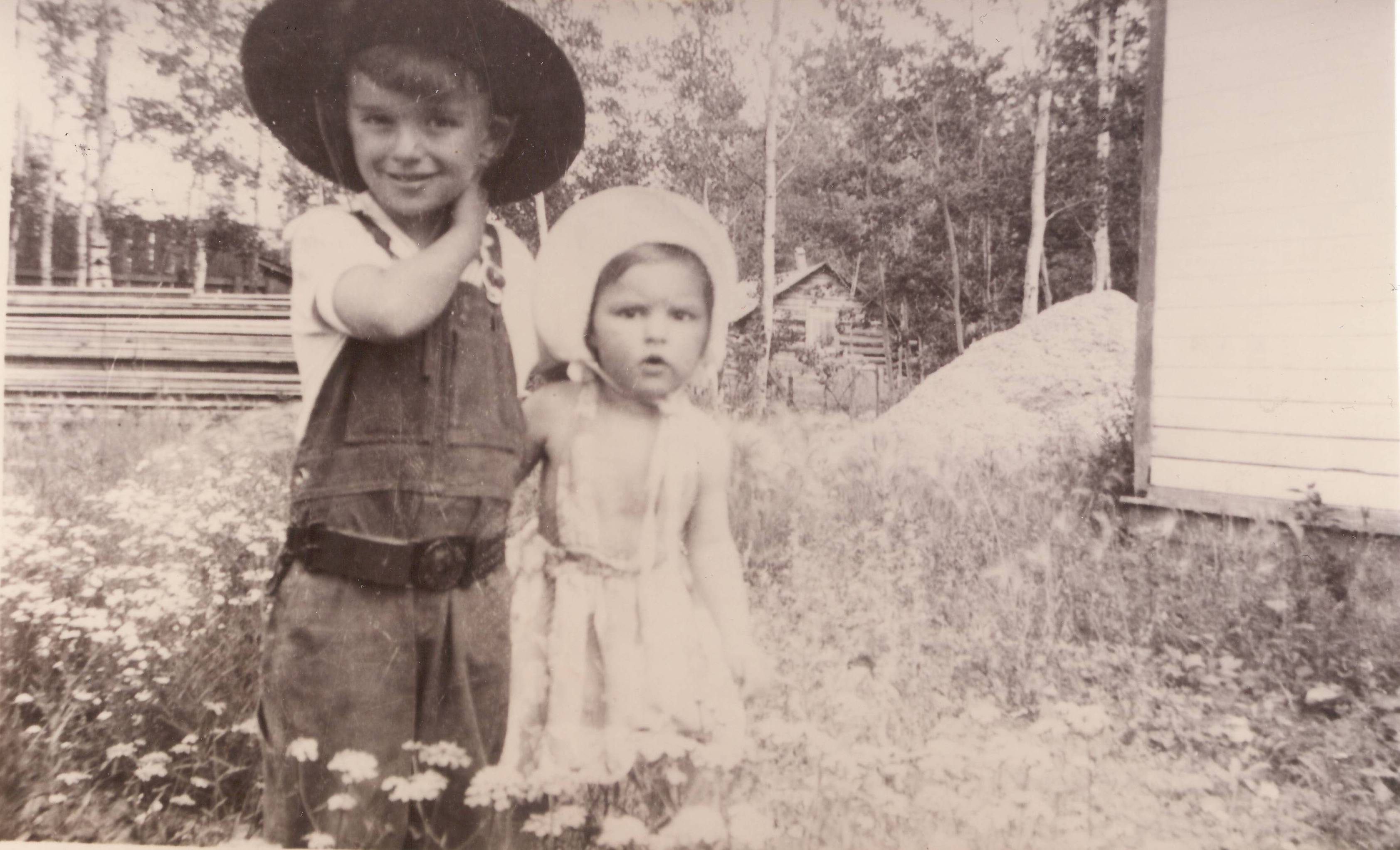 Does anyone recognize these two cuties? The pile of lumber and sawdust in the background indicate they are near a sawmill - but the flowers they are standing amongst, casual attire and contagious smirks have us longing for summer days!
990.4.106.54 / Ward, Vera
--EDIT--
On the left is Sheldon Clarke, on the right unknown.