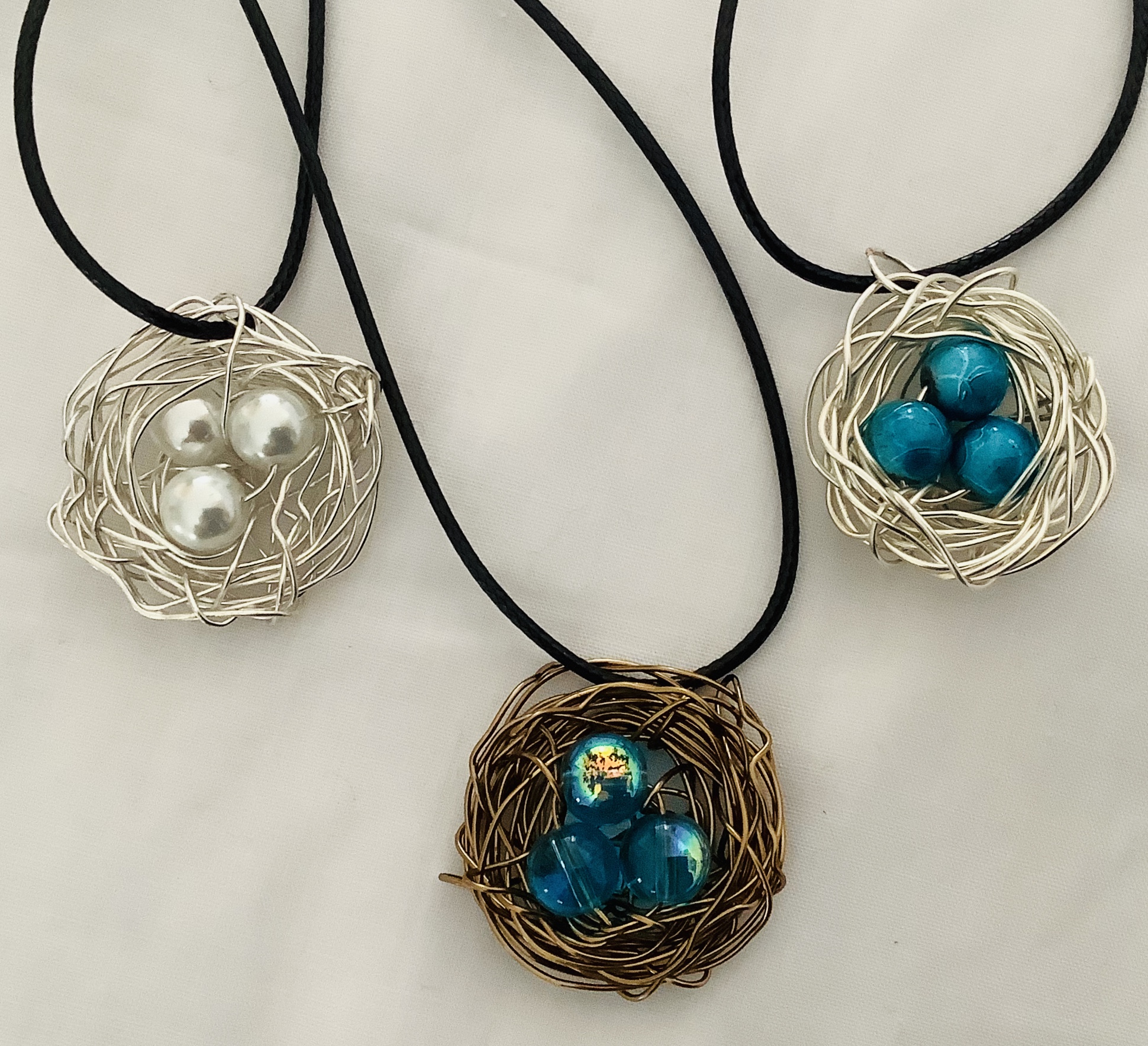 Bird Nest pendants are handwired individually using several types of wire and blue or white bead for the eggs. Any number of eggs can be added to the nest. Some folks have ordered the number of eggs of their family members.   $30.00