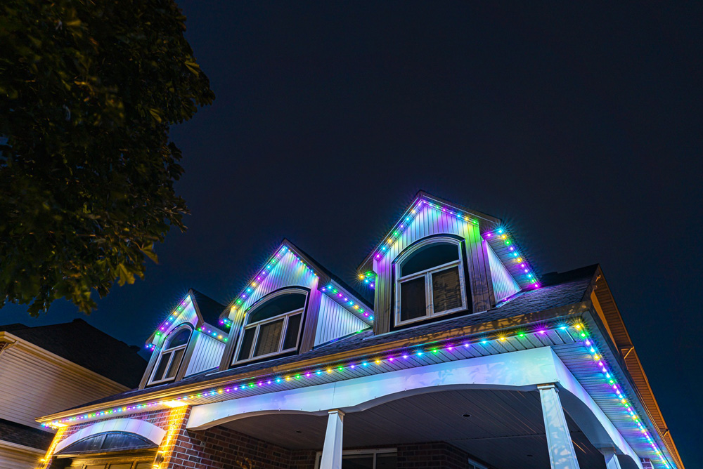 Pastel lights on the eaves of a house in the evening.