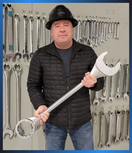 A man posing and holding a giant wrench