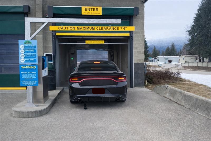 Rear view of a red sports car in a modern car wash facility with smoke effect.