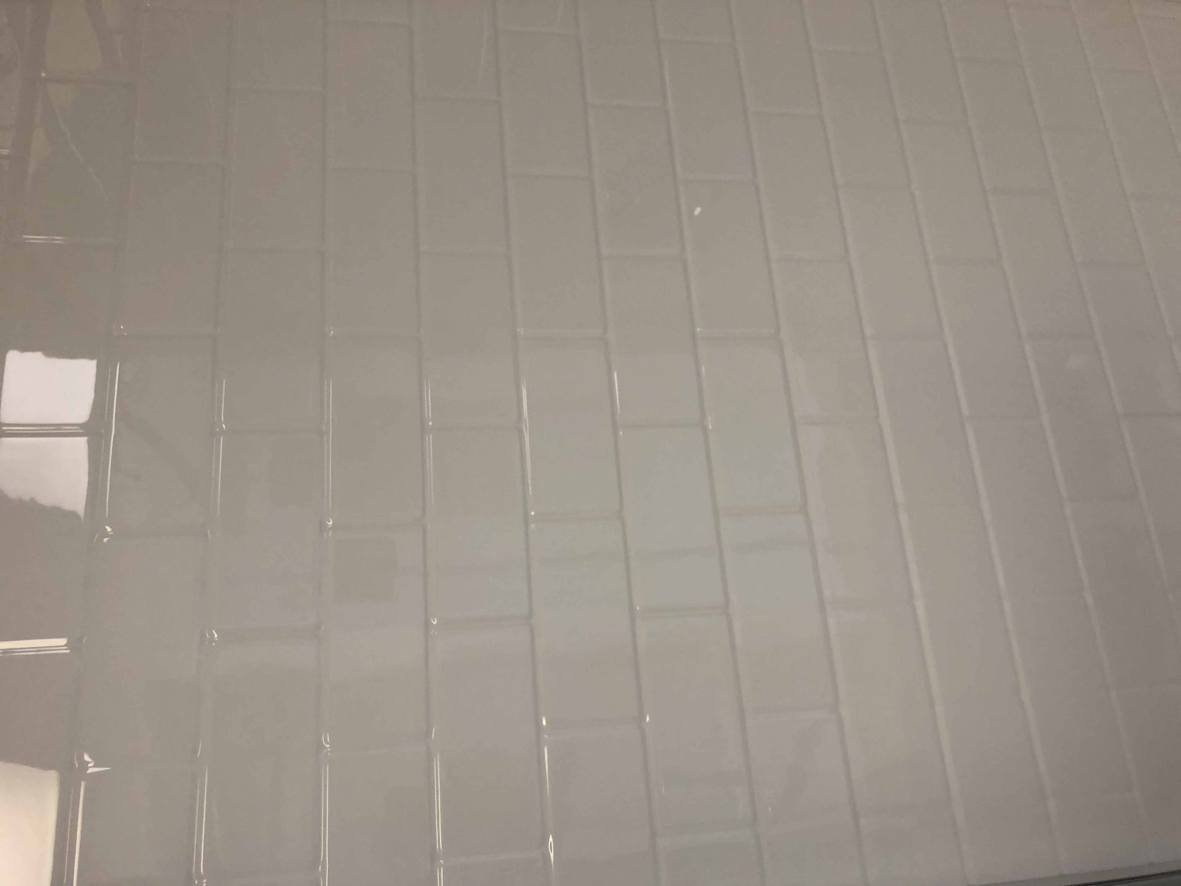 Modern bathroom with glass shower, vanity with round sink, wall-mounted mirror, decorative plants, and sleek lighting.