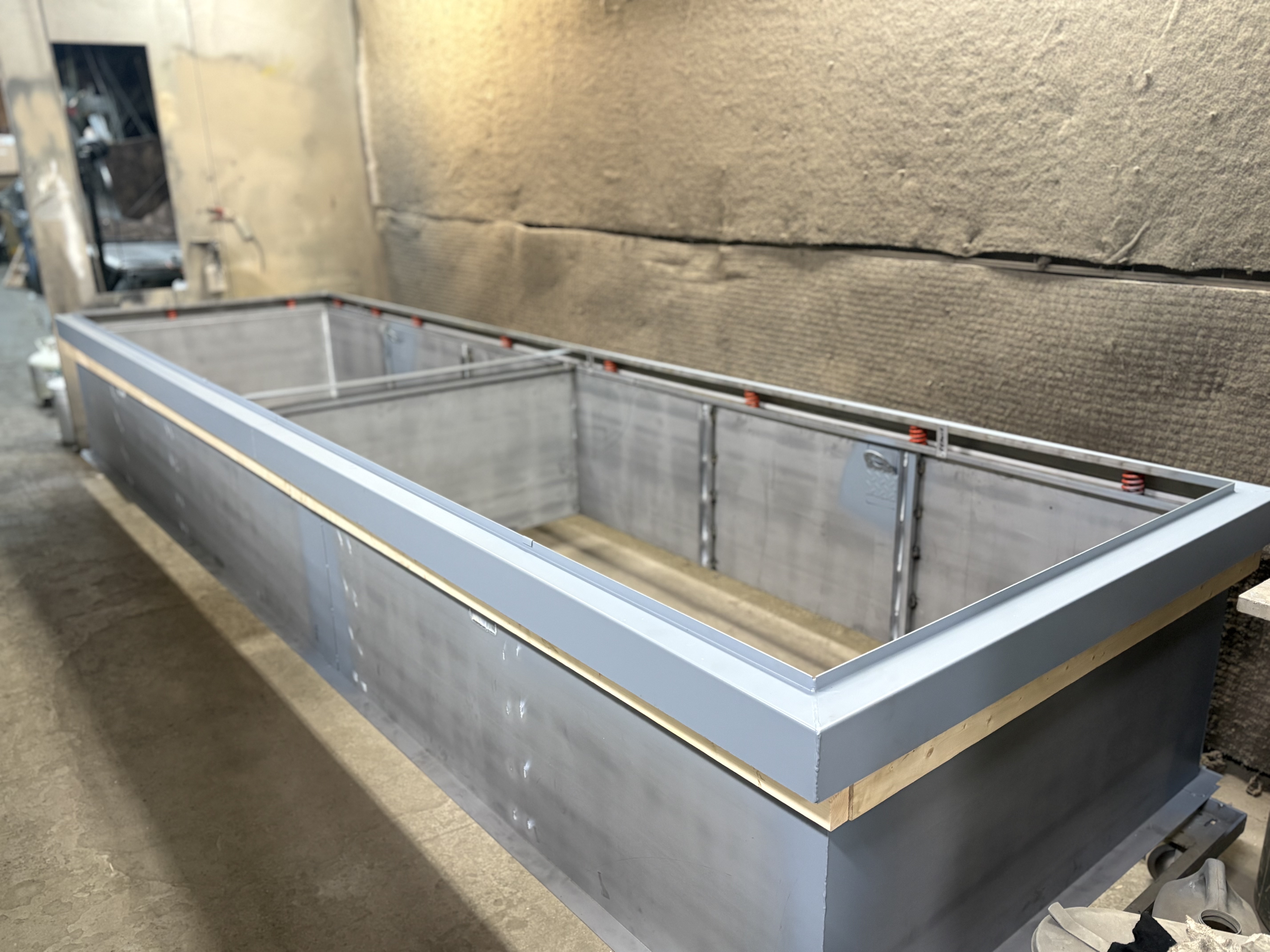 Large industrial metal frame in a workshop with insulated walls.