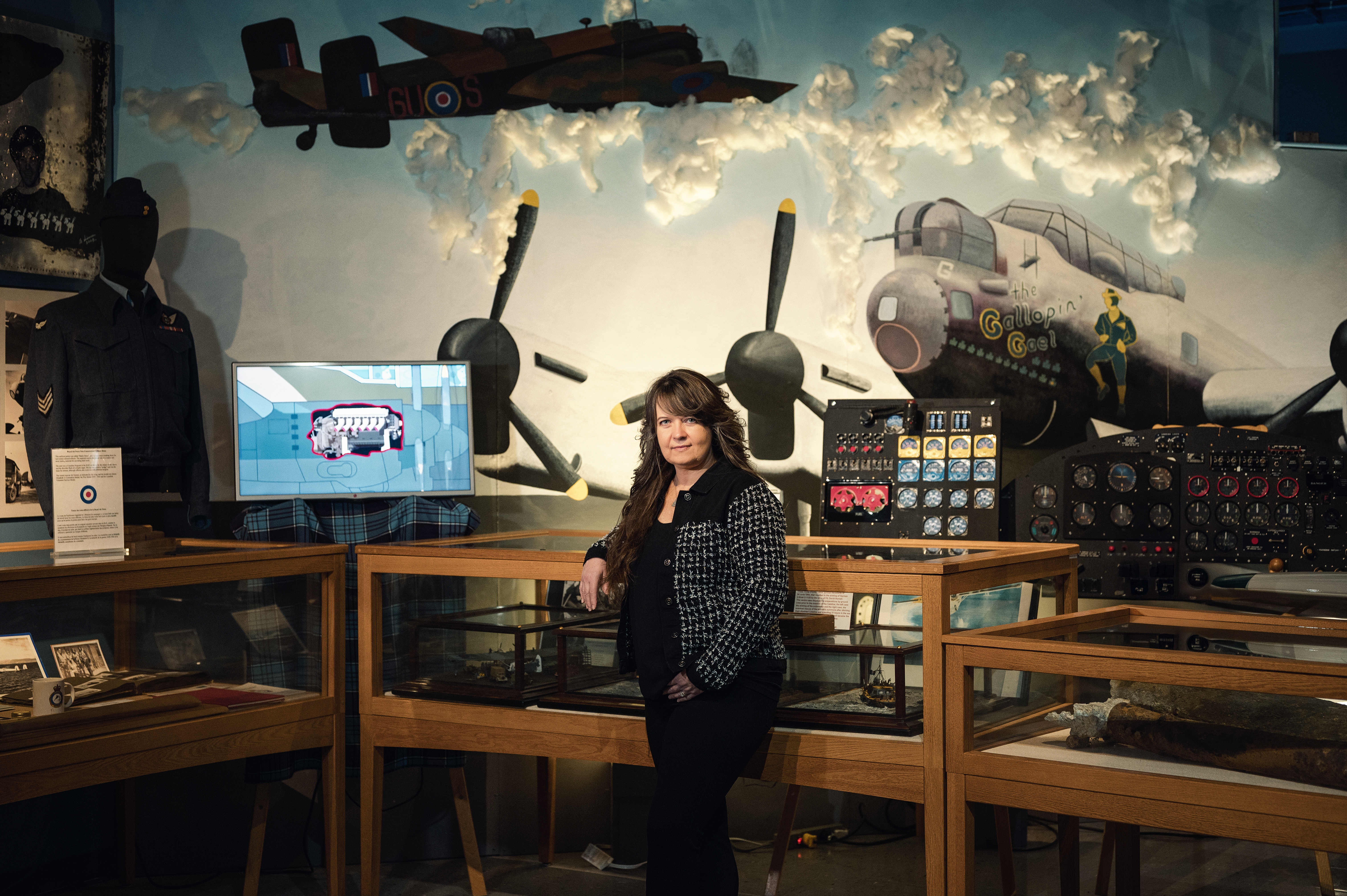 Smiling woman in business attire standing in a modern office hallway.