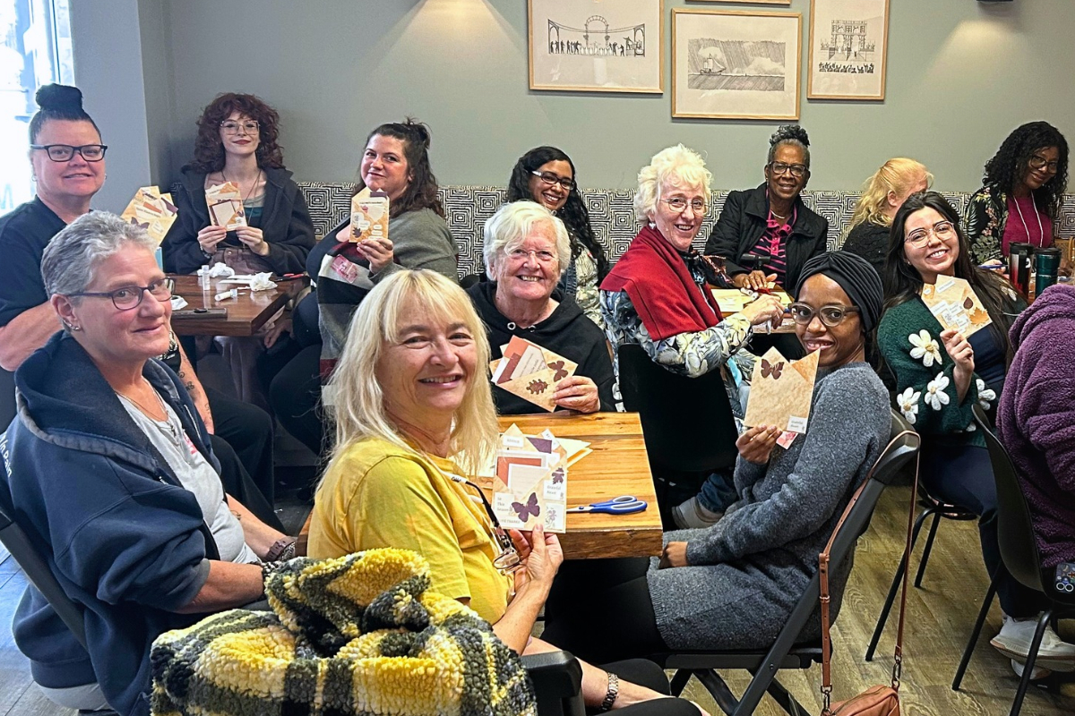 Women smiling and sharing their handmade paper crafts at a Created Me Creative gathering, celebrating creativity, learning, and community.
