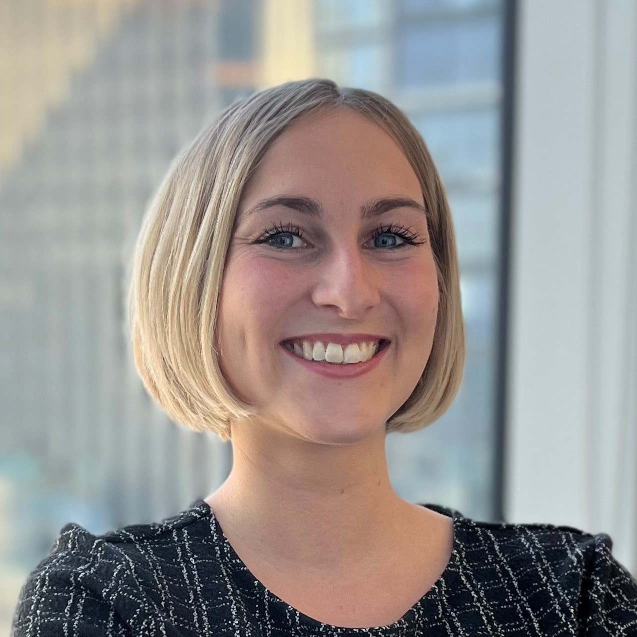 Business meeting with a presenter leading a discussion in a modern conference room, colleagues seated around tables with a large screen displaying presentation content.