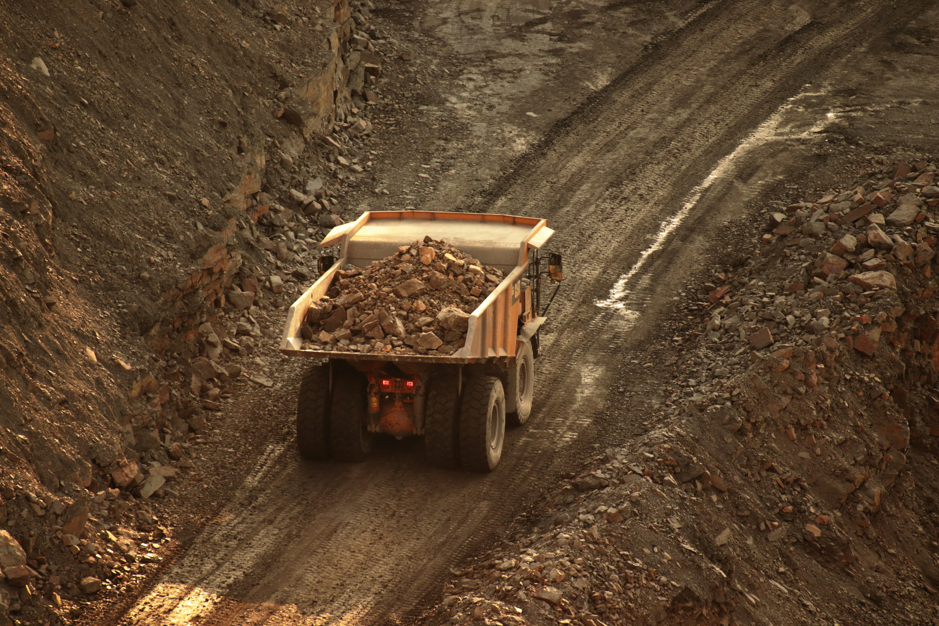 a dump truck driving down a dirt road