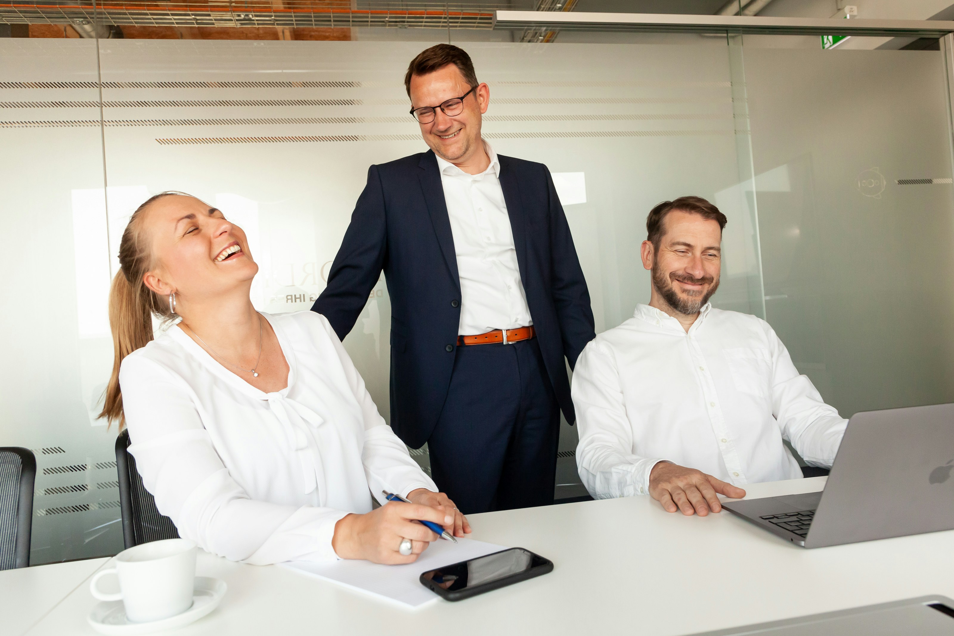 Group of professionals collaborating around a laptop in a modern office setting. Group of professionals collaborating around a laptop in a modern office setting.