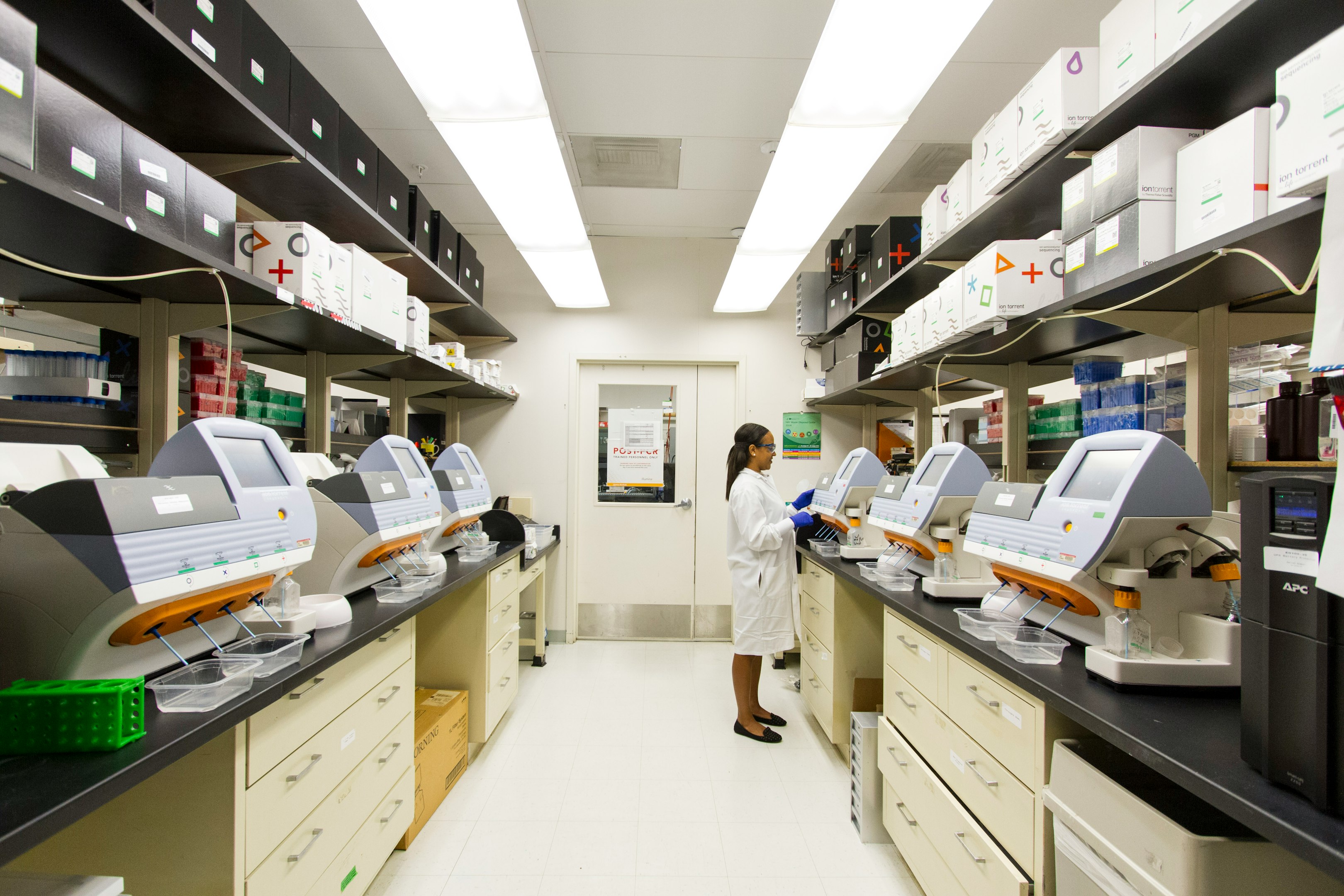 Scientist working in a modern laboratory with advanced equipment and organized shelving.