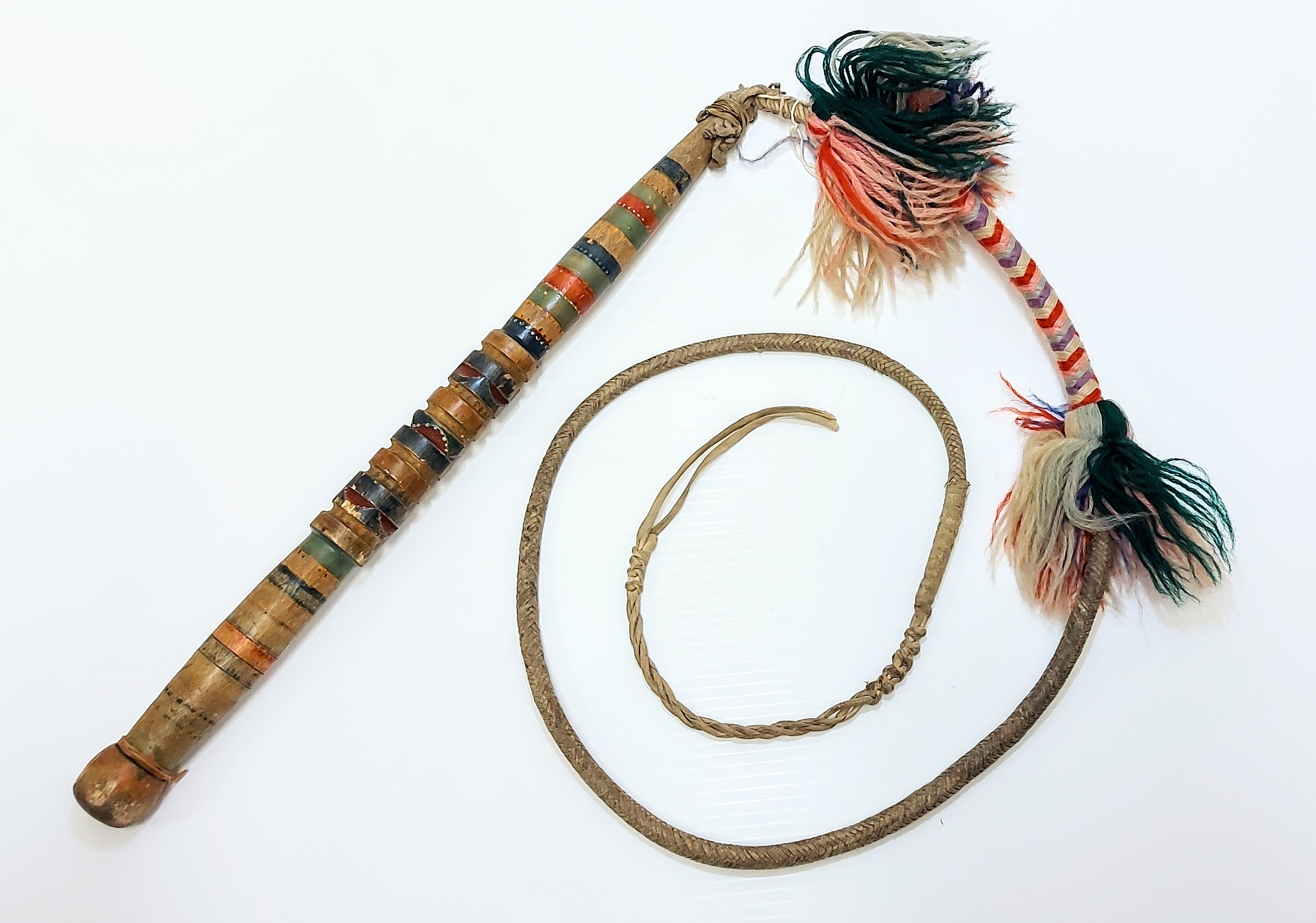 This is a homemade whip used for Dog Mushing. It is beautifully decorated with yarn detailing and an ornately carved (and painted) wooden handle. It generally would not be used to strike the dogs -rather it would be "cracked" which would make noise to encourage the dogs to run. Dog sled teams were a major source of transportation in the area from the early years up until 1950 or so. Kids would mush dogs to school, mail was brought by dog team and trappers relied on them while on the trapline. 
2004.01.08 / Clarke, Pete + Doris