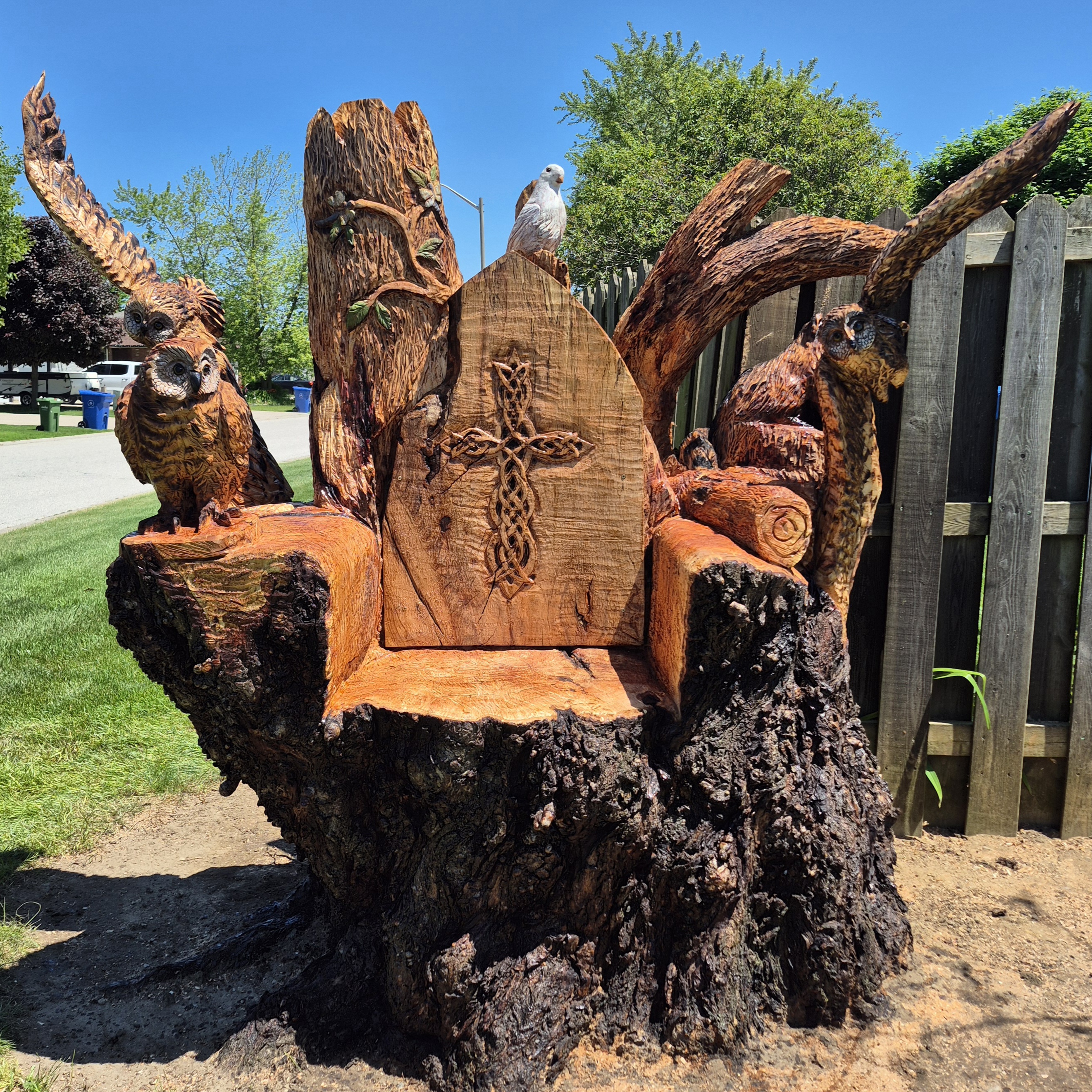 Chainsaw wood carving artists creating animal sculptures in a sunny backyard garden