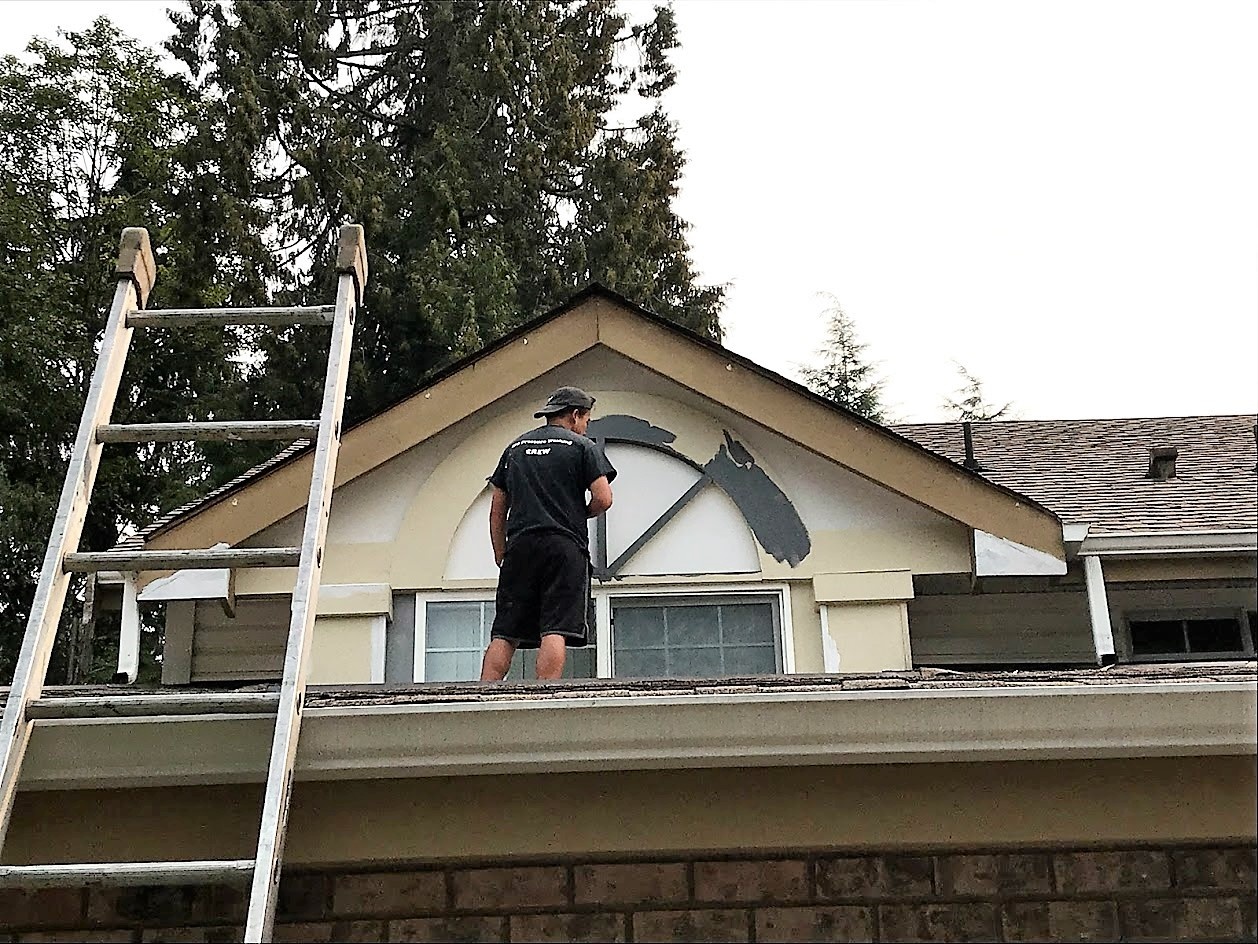 Painting trim on exterior of house.