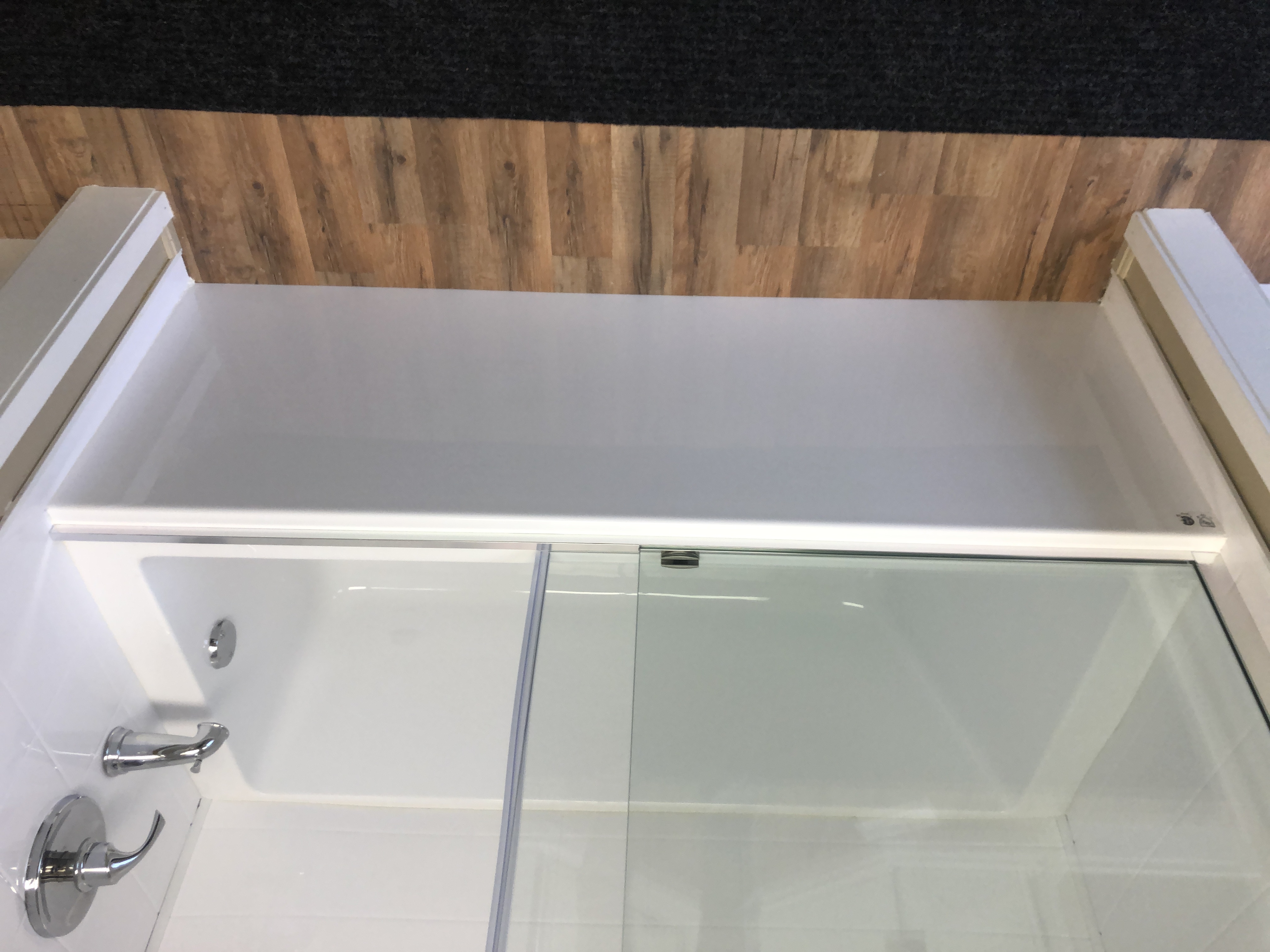 Modern bathroom with a white freestanding tub near a large window, floating vanity with sink, and glass-enclosed shower.