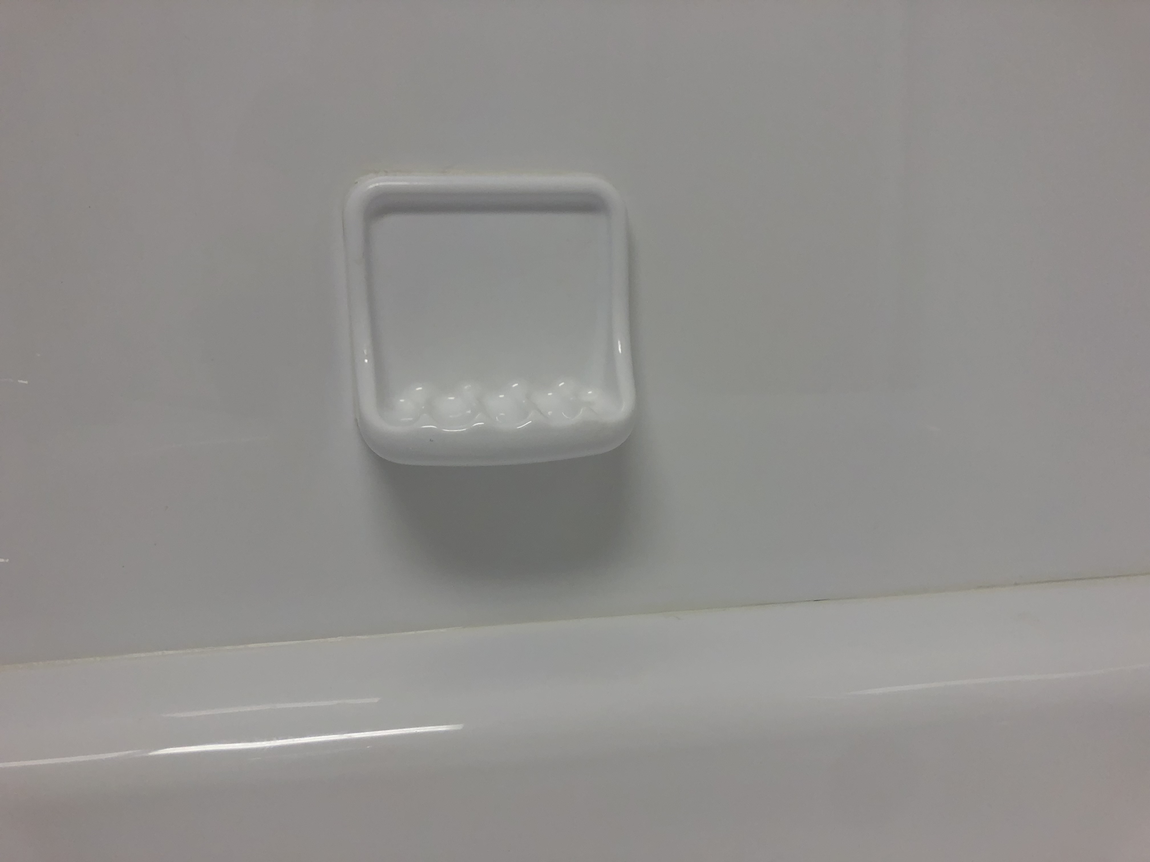 Modern bathroom with freestanding tub, large mirror, white cabinets, and potted plants by a large window.