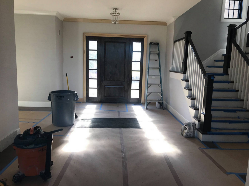 esidential entryway in active post-renovation condition with protective coverings, equipment, and recovery preparation before occupancy