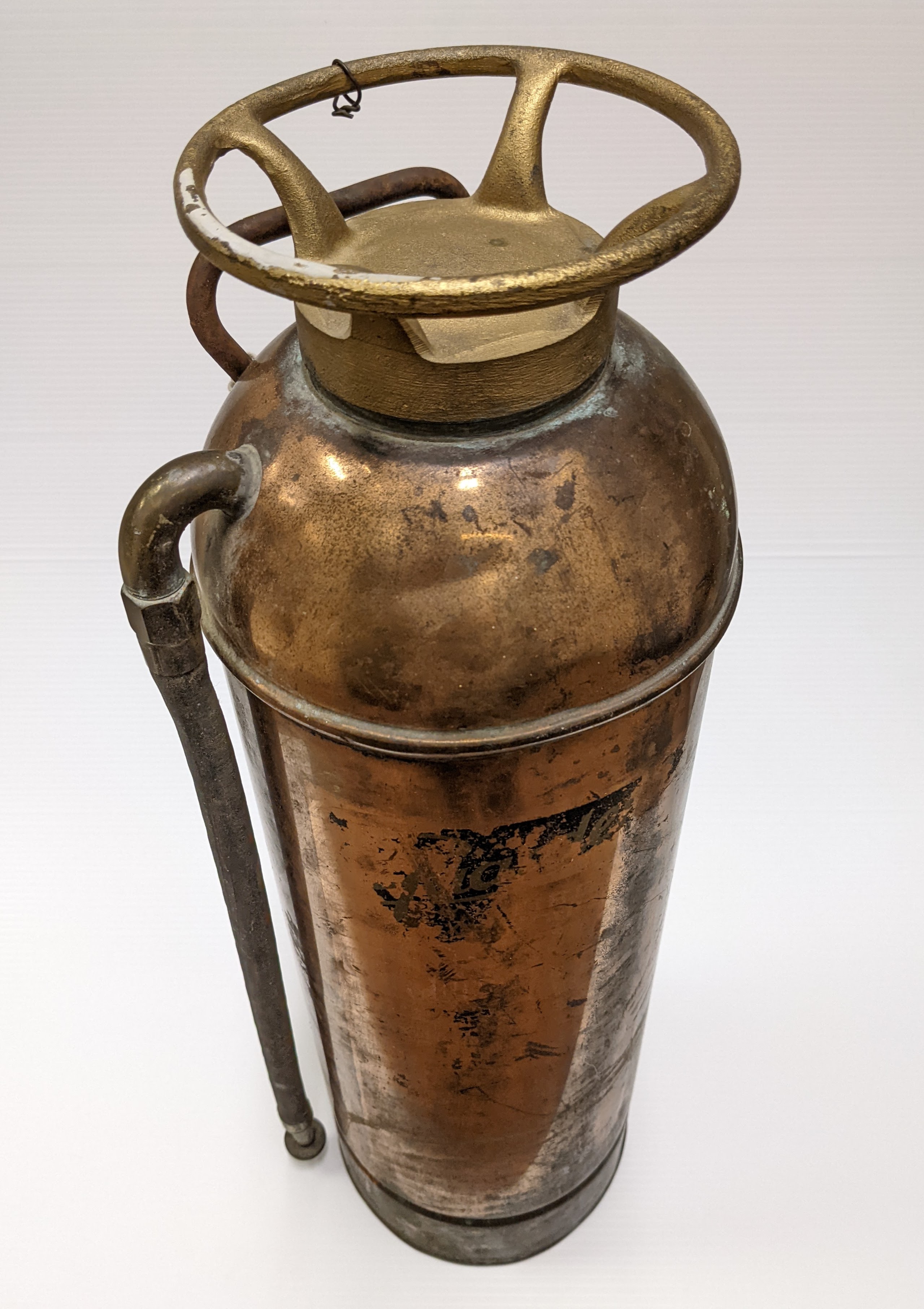 This fire extinguisher comes from the Fort Vermilion Experimental Farm. "Guardene" brand, it is an inversion style extinguisher - meaning to use it one has to flip it upside down and hold it from the bottom. This action causes the internal elements (hydrochloric acid and Bicarbonate soda dissolved in water) to mix and react - producing carbon dioxide gas. The pressure created by this chemical reaction then forces the contents of the tank (water, acid, and carbon dioxide) out the rubber hose for the operator to direct on the flames. The soldering job on the back indicate the tank was repaired at one point and the rivets date it as pre-1942.
17/01/2022
2020.07.18 / Cranna, Marilee
