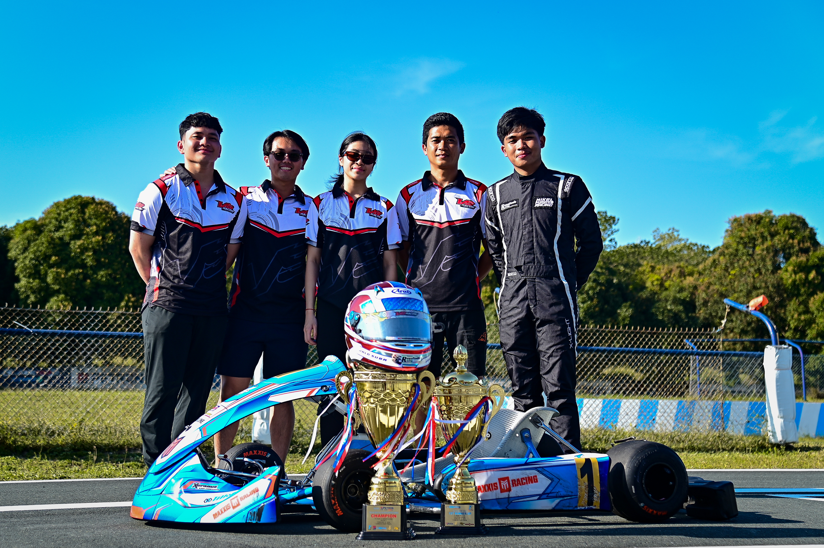 Close-up of a kart racer in a red and black helmet, focused on the track with a second racer blurred in the background. Close-up of a kart racer in a red and black helmet, focused on the track with a second racer blurred in the background.