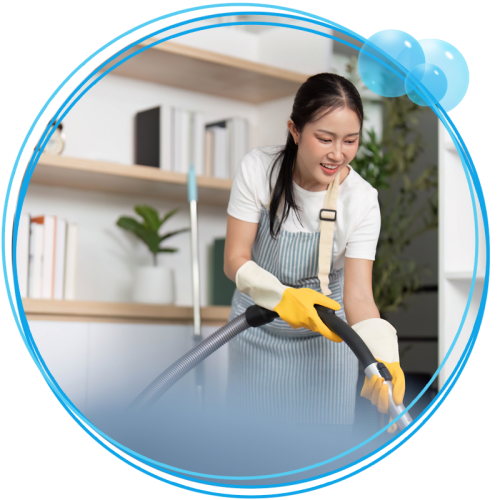 Woman vacuuming the floor behind a blurred out sofa.