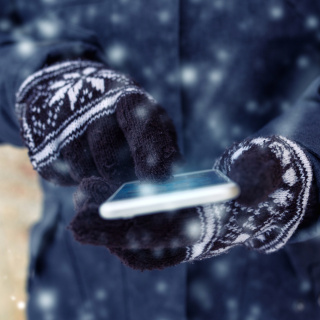 Person wearing mittens and using a cell phone