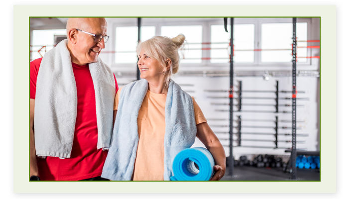 A senior couple in the gym smiling at each other